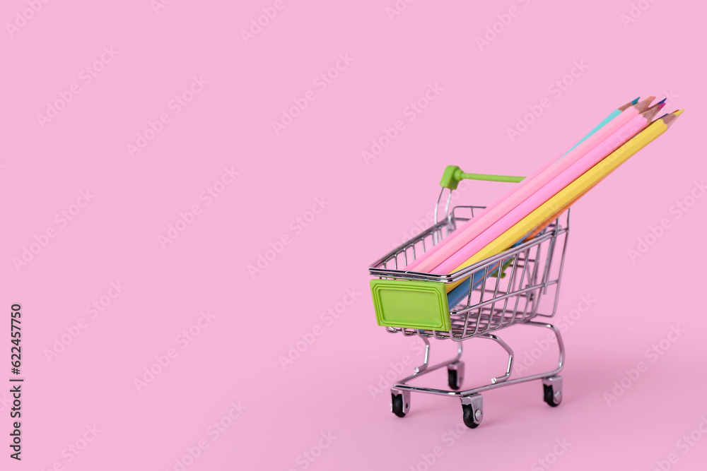 Shopping cart with pencils on pink background