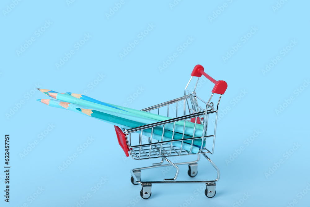 Shopping cart with pencils on blue background