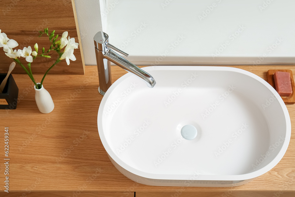 White sink and vase with flowers on table in bathroom