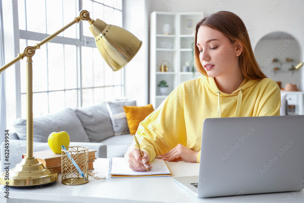 Female student writing in notebook at home