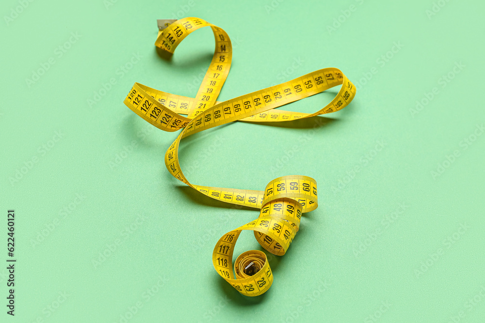 New yellow measuring tape on green background