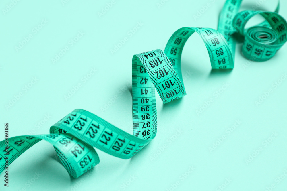 New measuring tape on turquoise background, closeup