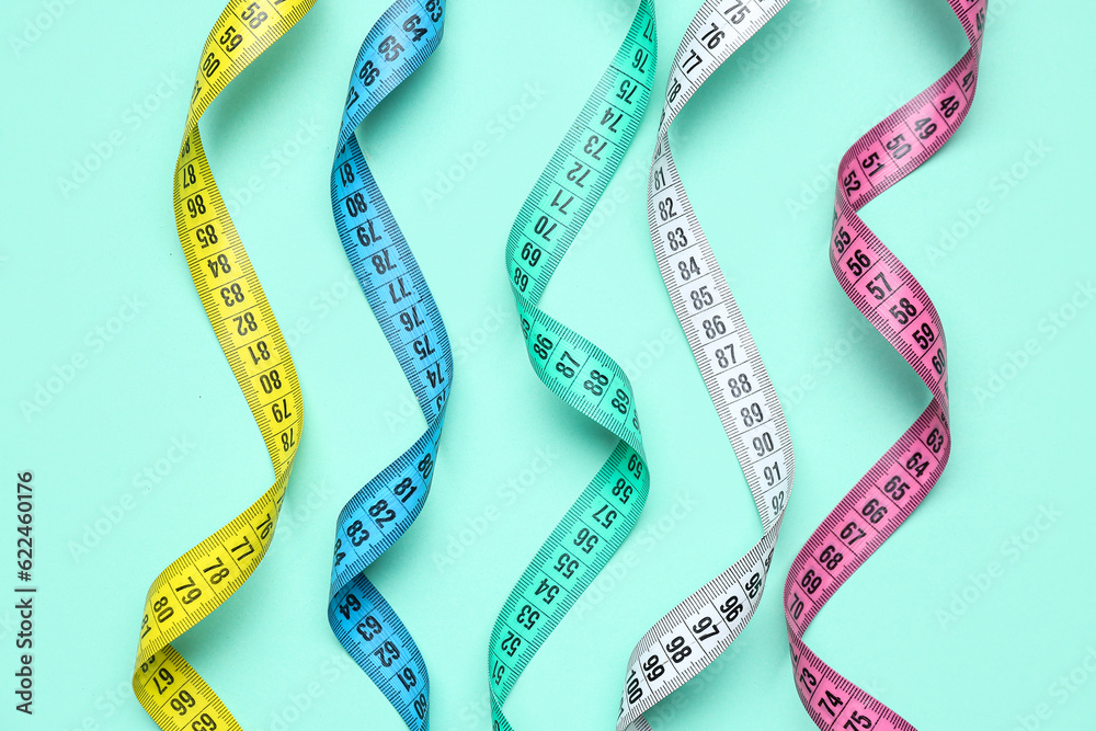 Colorful measuring tapes on turquoise background