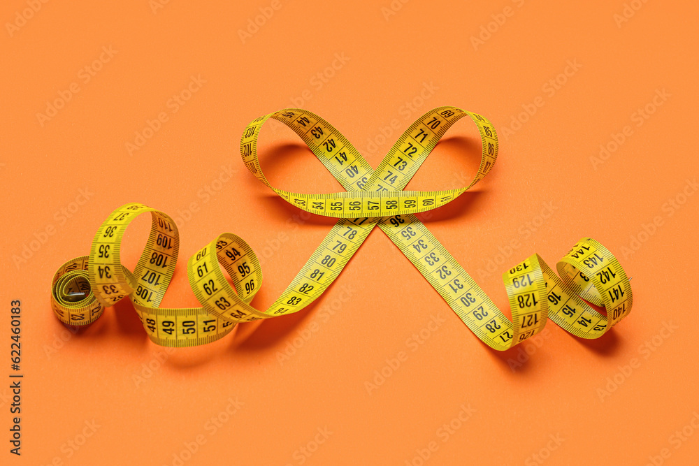 Yellow measuring tape on orange background