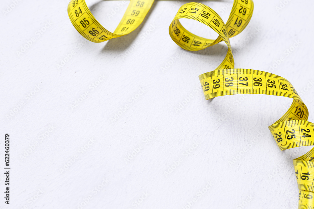 New yellow measuring tape on white background, closeup