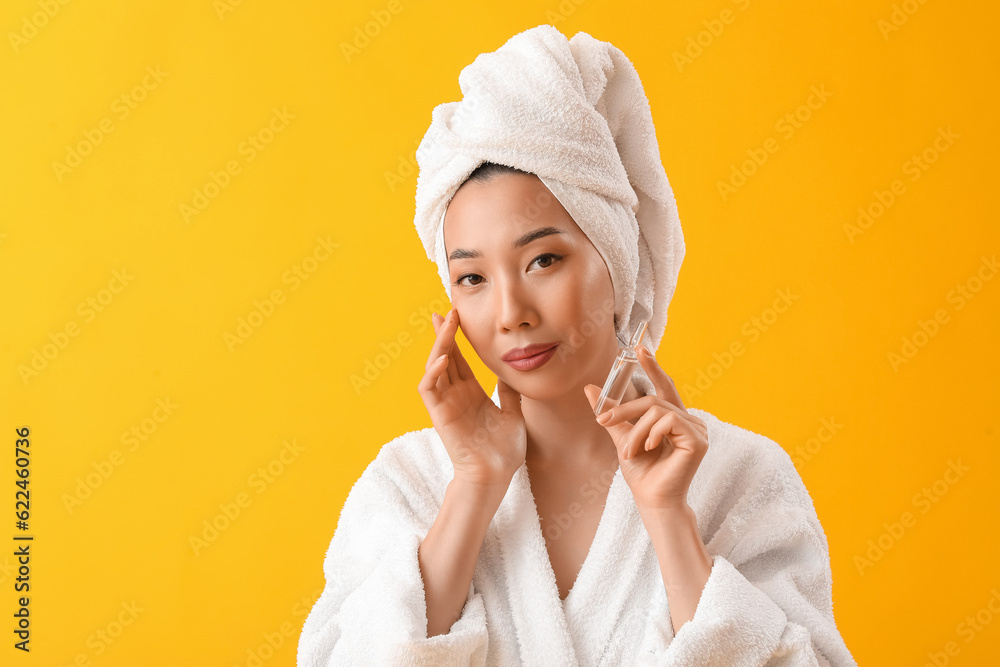 Beautiful Asian woman with ampule on yellow background. Skin care concept