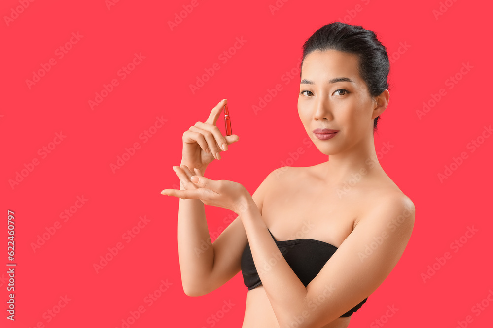 Beautiful Asian woman with ampule on red background. Skin care concept