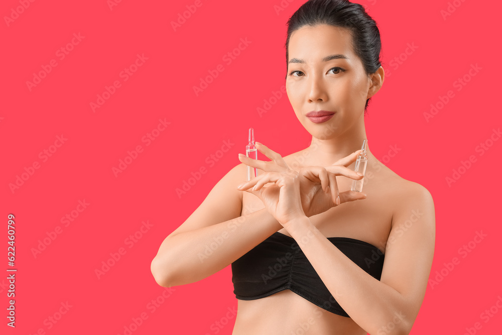 Beautiful Asian woman with ampules on red background. Skin care concept