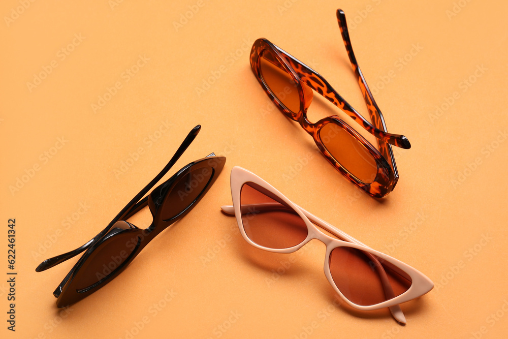 Different stylish eyeglasses on orange background