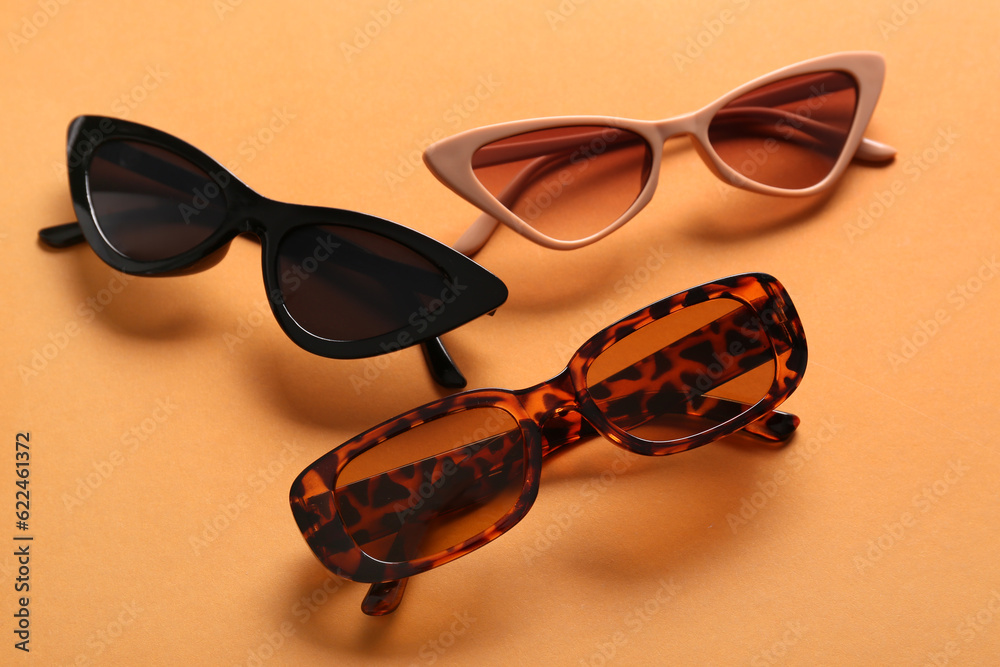 Different stylish eyeglasses on orange background, closeup