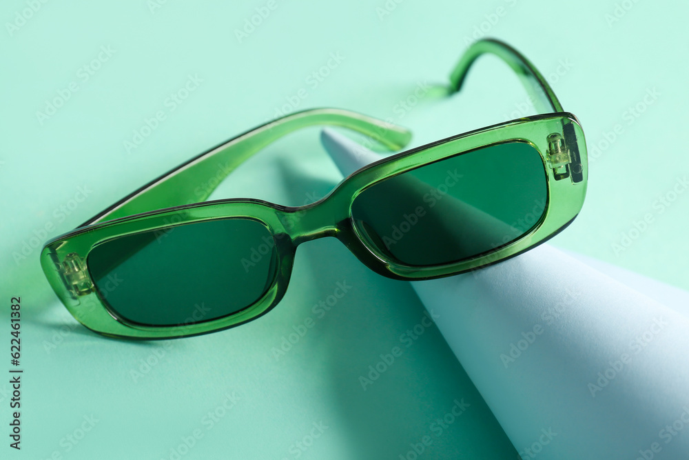 Modern eyeglasses on turquoise background, closeup