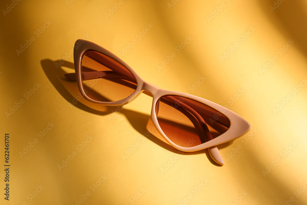 Stylish eyeglasses on yellow background, closeup