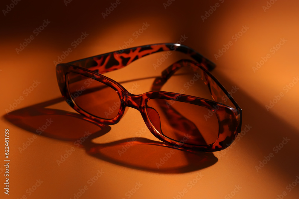 Stylish eyeglasses on orange background, closeup