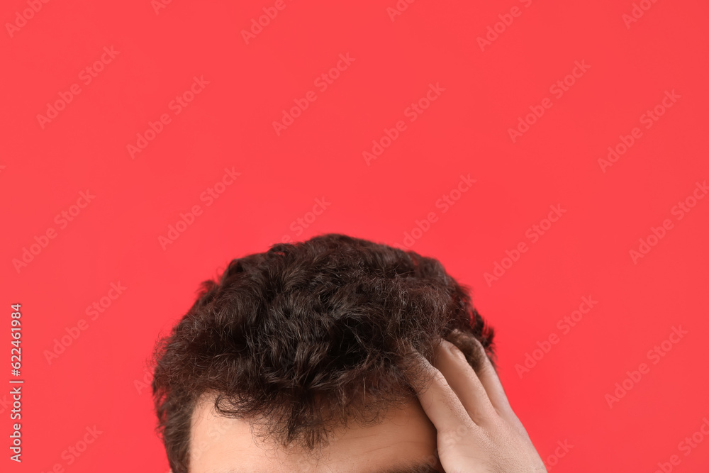 Young brunette man with stylish hairdo on red background, closeup