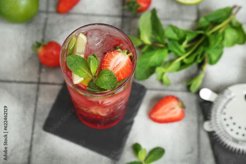 Glass of fresh strawberry mojito on tile background, closeup