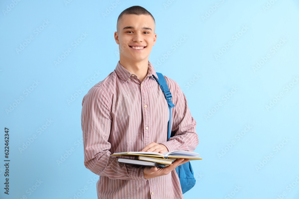 Male student with backpack and books on blue background