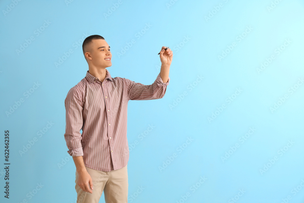 Male student with pen on blue background