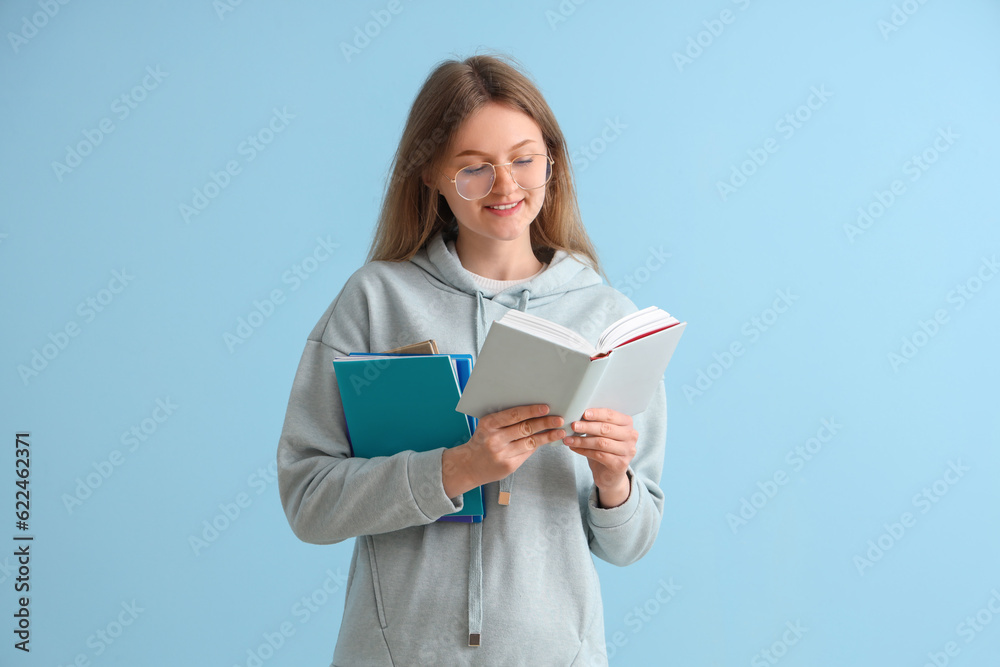 Happy female student with different books on blue background