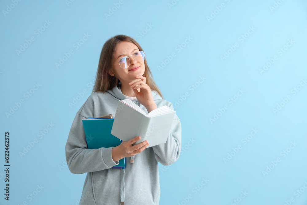 Happy female student with different books on blue background