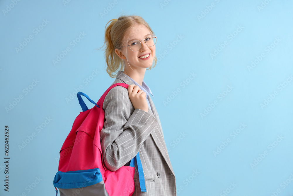 Happy female student with backpack on blue background