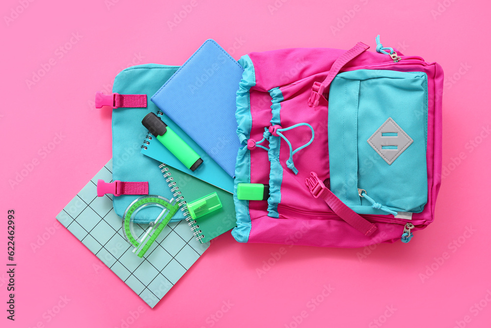 Color school backpack with notebooks, protractor and markers on pink background