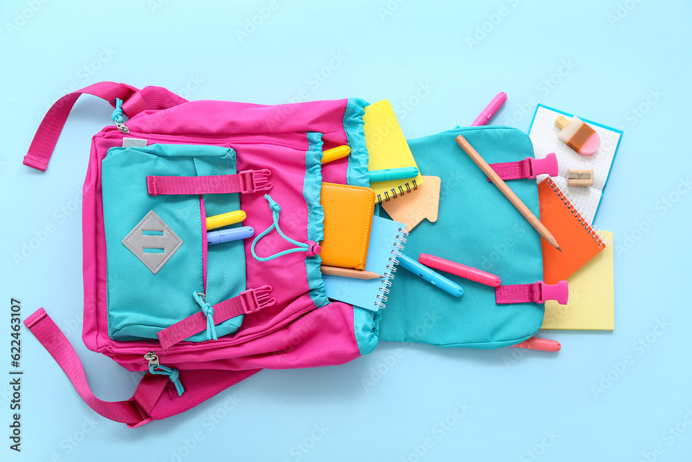 Pink school backpack with markers and notebooks on blue background