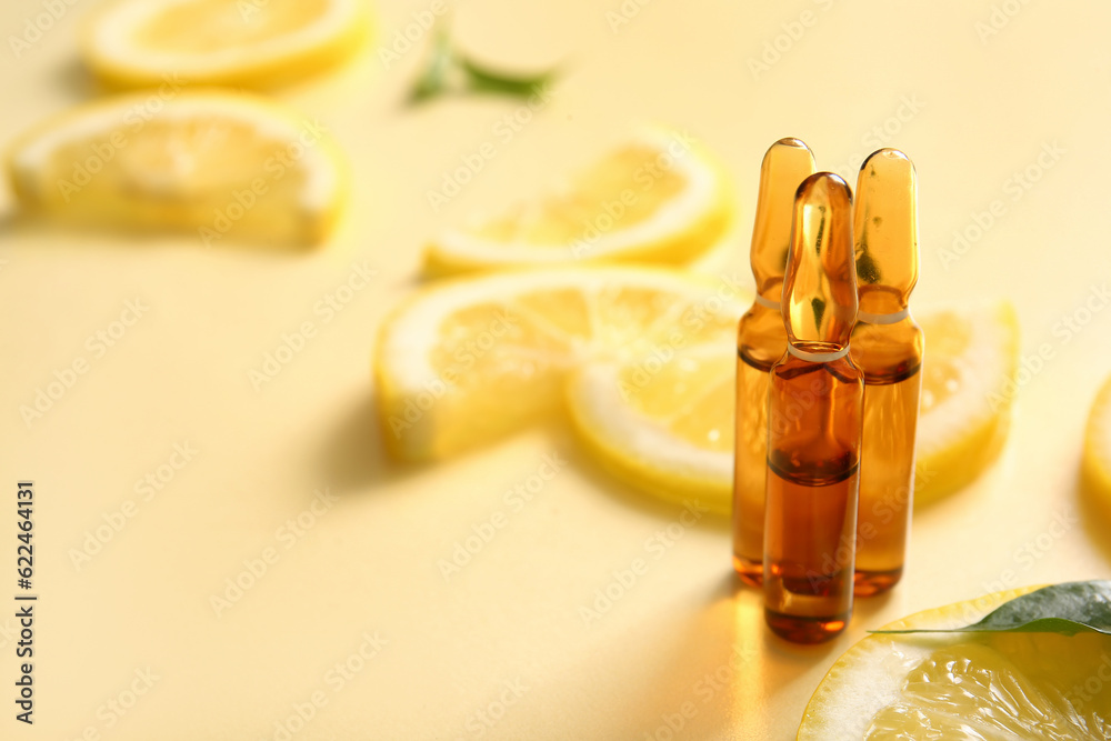 Ampoules with vitamin C and lemon slices on yellow background