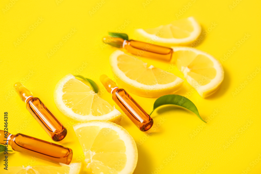 Ampoules with vitamin C and lemon slices on yellow background