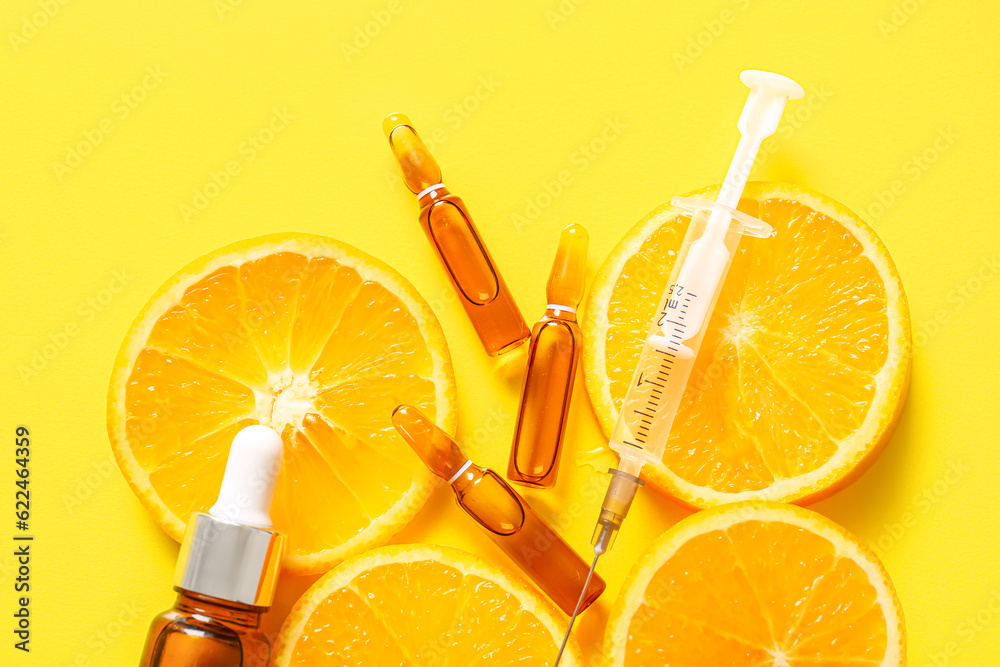 Ampoules with vitamin C, syringe, bottle of essential oil and orange slices on yellow background, cl