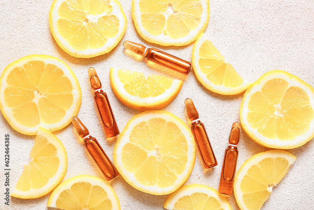 Ampoules with vitamin C and lemon slices on light background