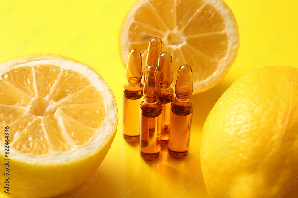 Ampoules with vitamin C and lemon on yellow background, closeup