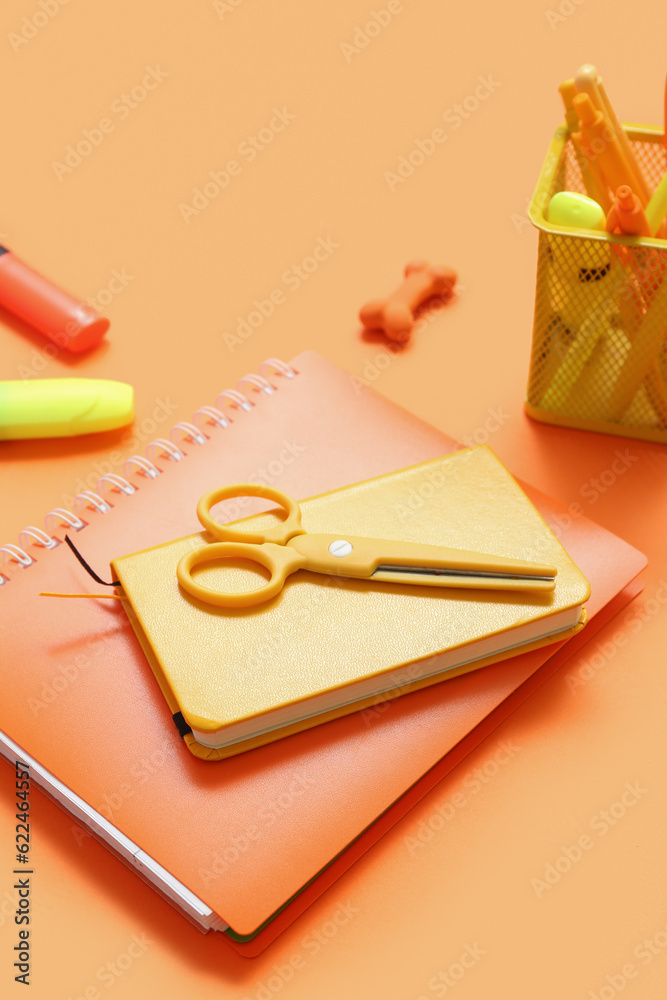 Notebooks with different stationery on orange background, closeup