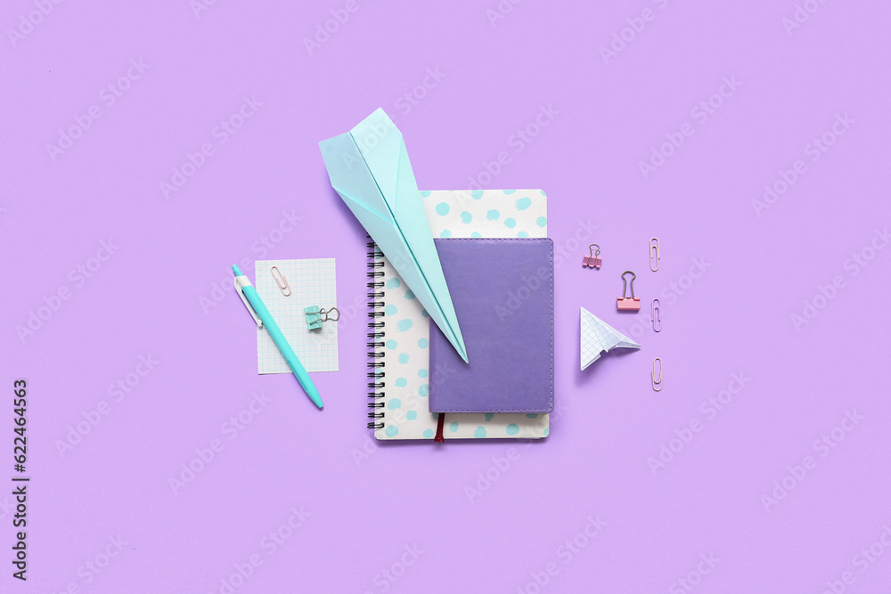 Notebooks, paper planes and school stationery on purple background