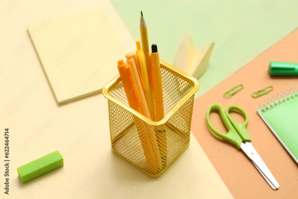 Cup with school stationery on color background, closeup