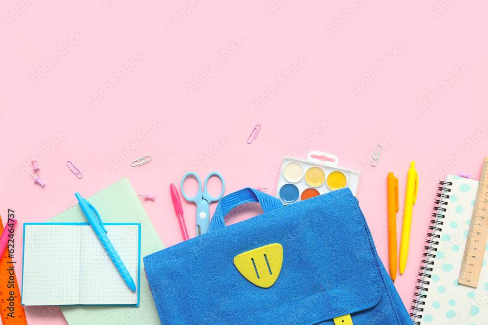 School backpack with different stationery on pink background