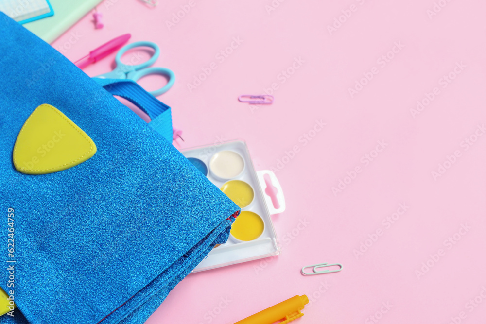 School backpack with different stationery on pink background, closeup