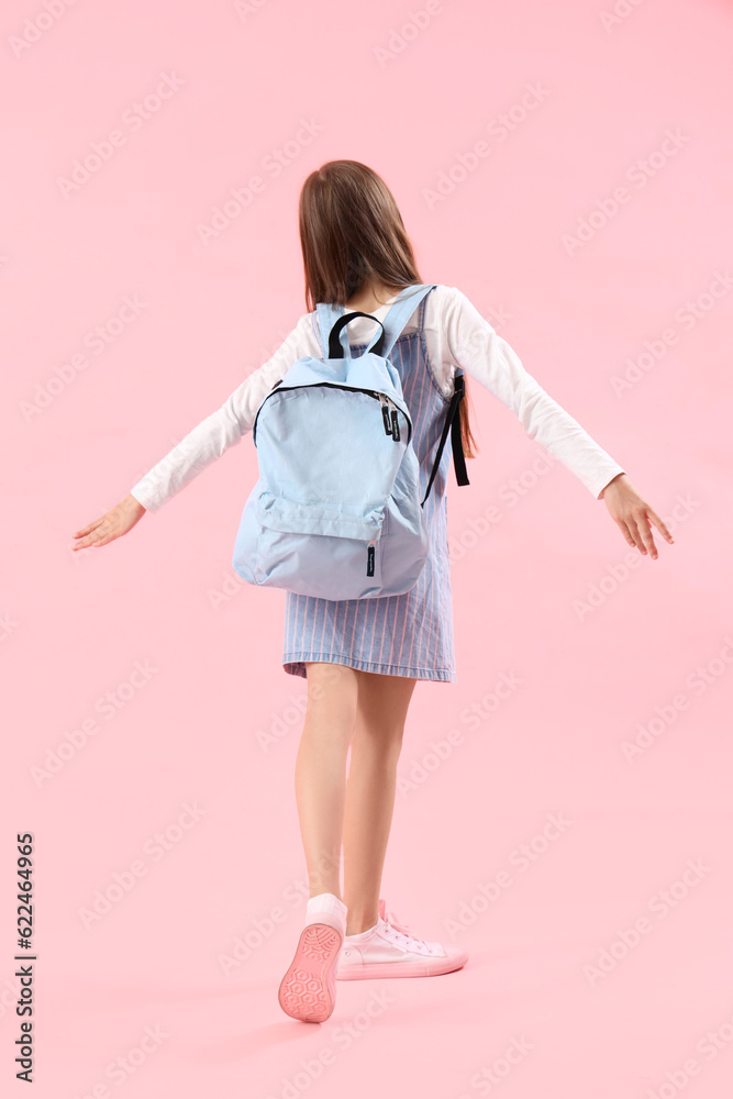 Little girl with schoolbag on pink background, back view