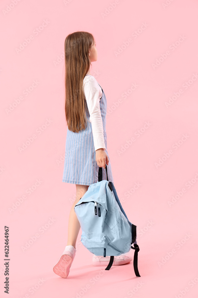 Little girl with schoolbag on pink background