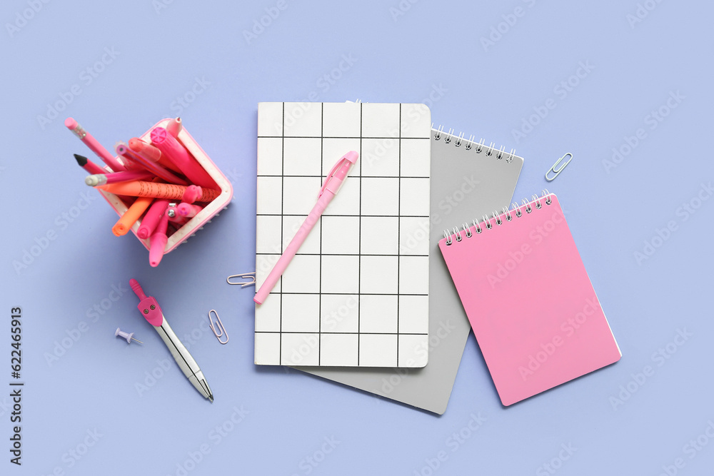 Notebooks and school stationery on lilac background