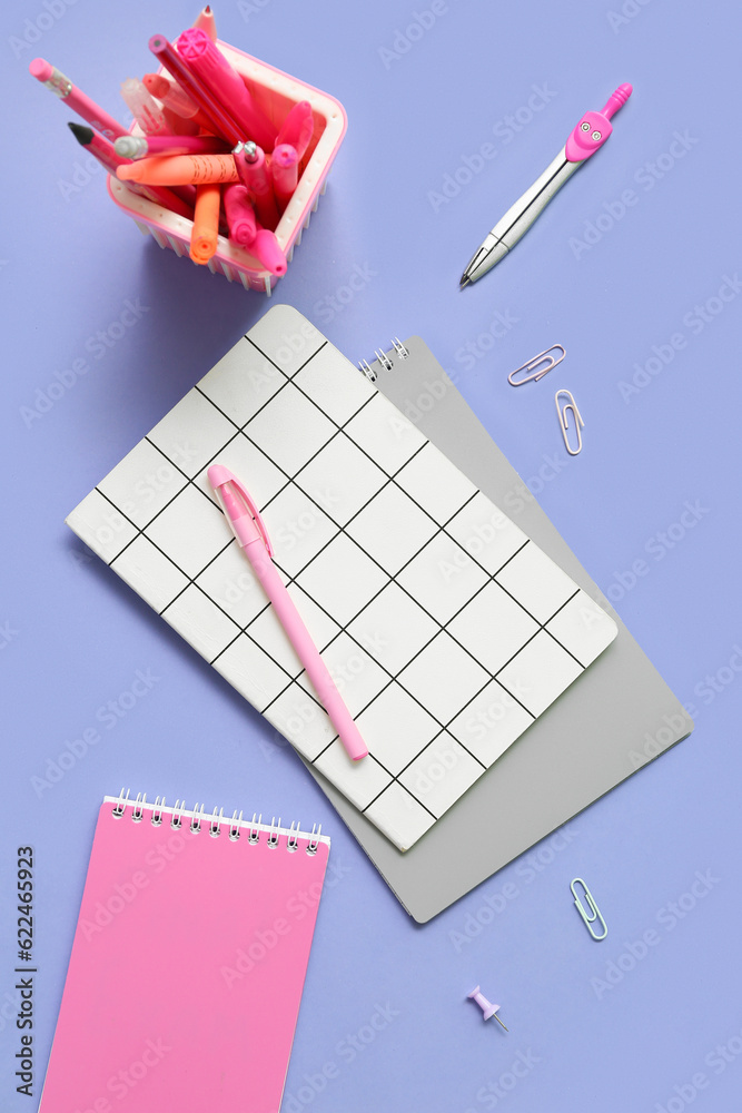 Notebooks and school stationery on lilac background