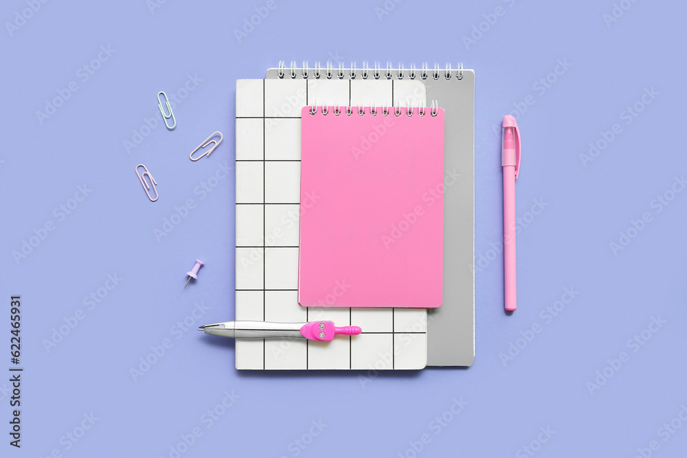 Notebooks and school stationery on lilac background