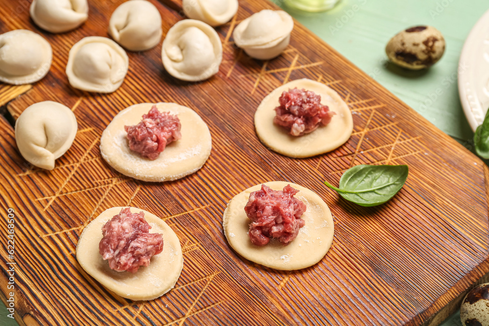 Raw dough with minced meat and uncooked dumplings on table