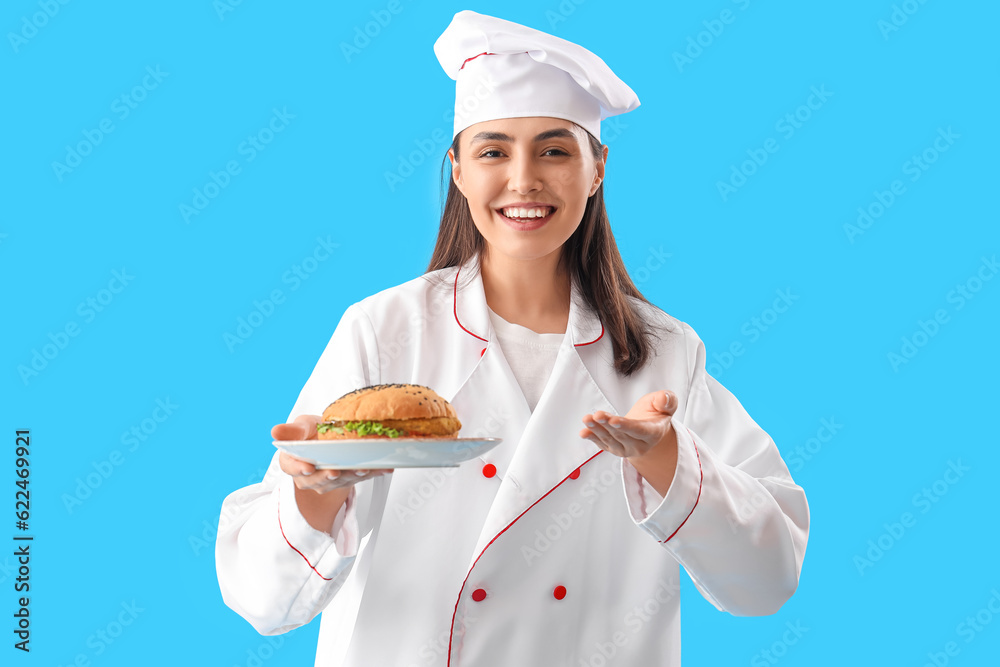 Female chef with tasty burger on blue background