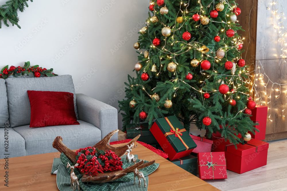 Interior of living room with Christmas tree, gift boxes, grey sofa and coffee table