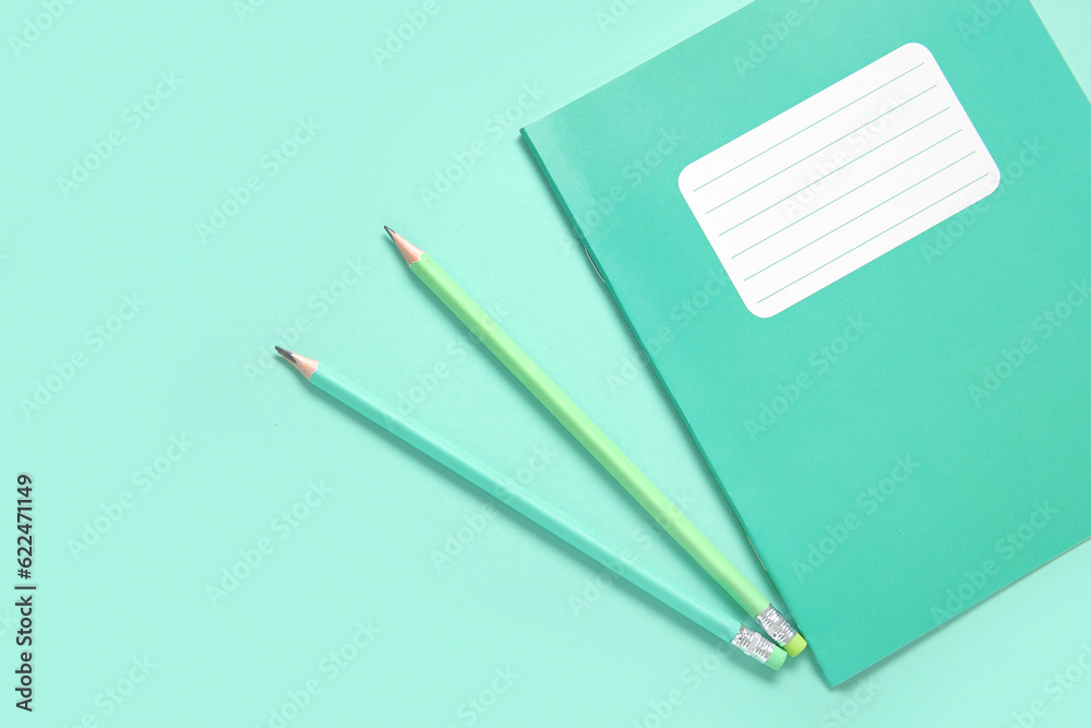 Notebook with pencils on turquoise background