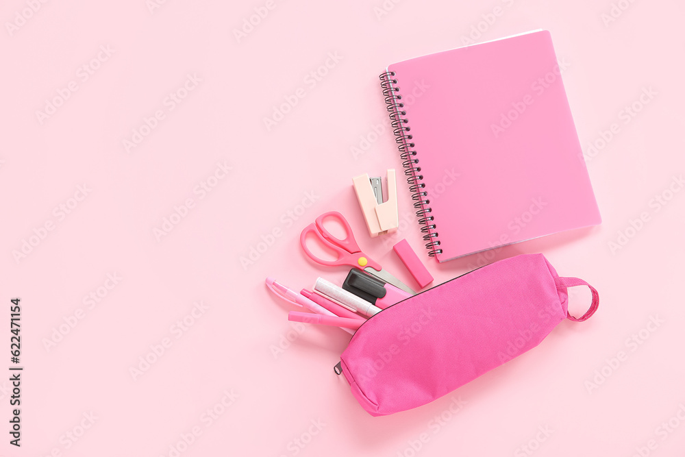 Notebook and pencil case with different stationery on pink background