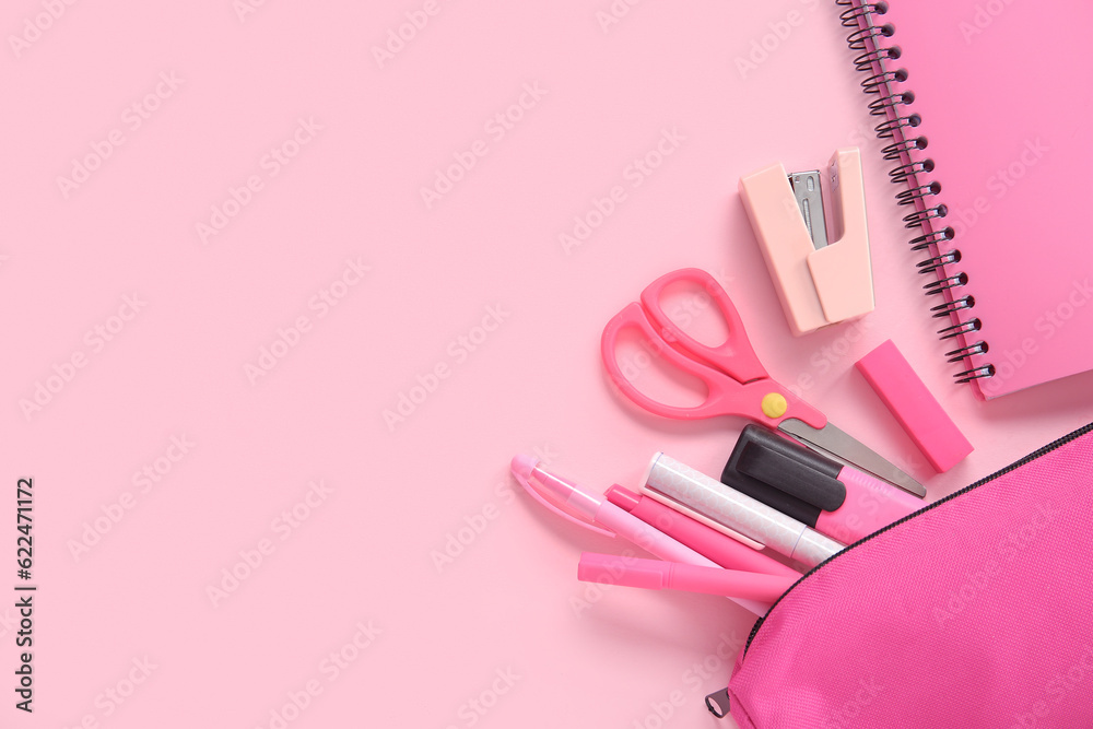 Notebook and pencil case with different stationery on pink background