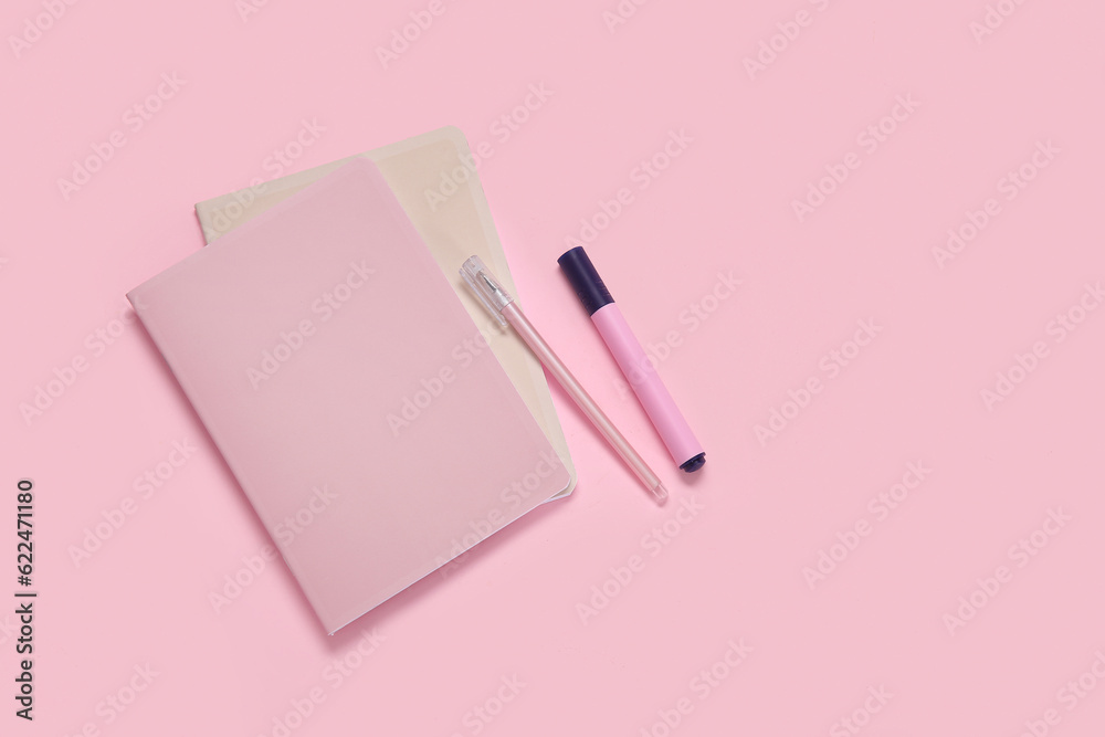 Notebook with pen and marker on pink background