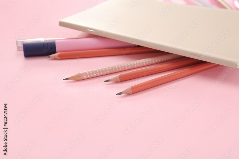 Notebook with different stationery on pink background