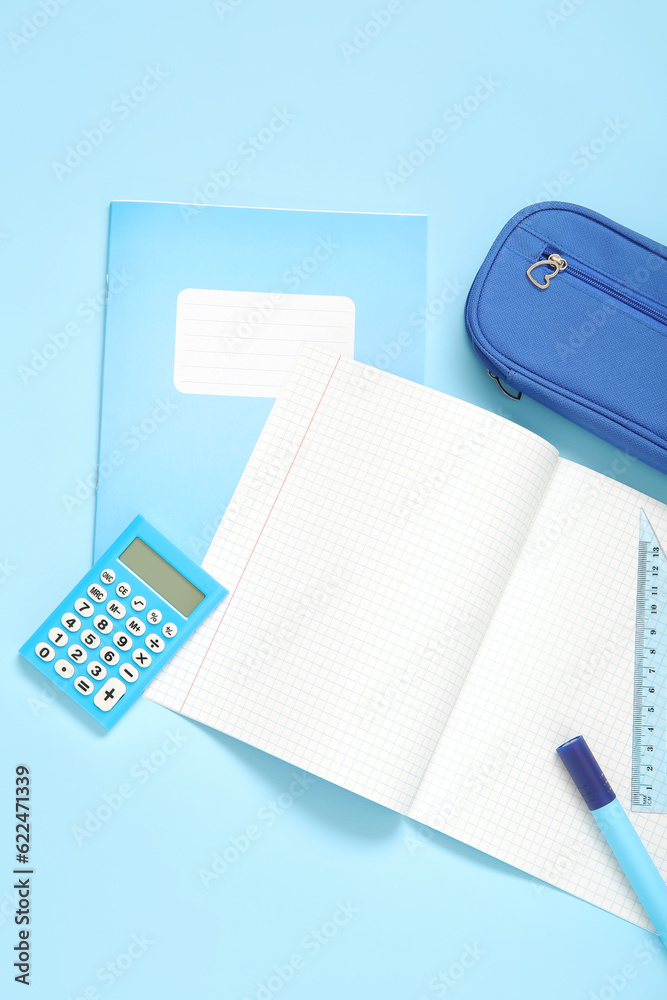 Notebooks with pencil case and different stationery on blue background